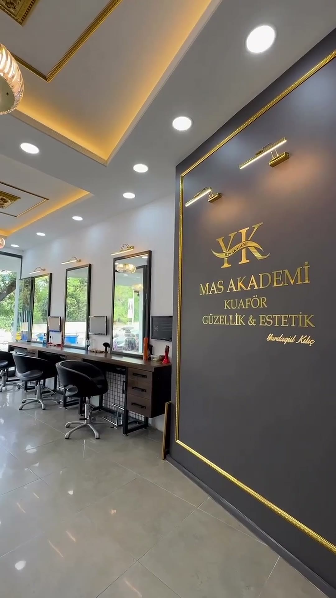 Mas Kuaför ve Güzellik Salonu: kömür grisi duvarda altın harfli logo, aynalar ve koltuklar